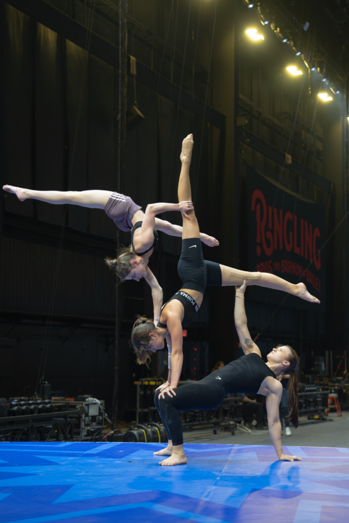 Three performers balancing on top of another during Ringling rehearsals